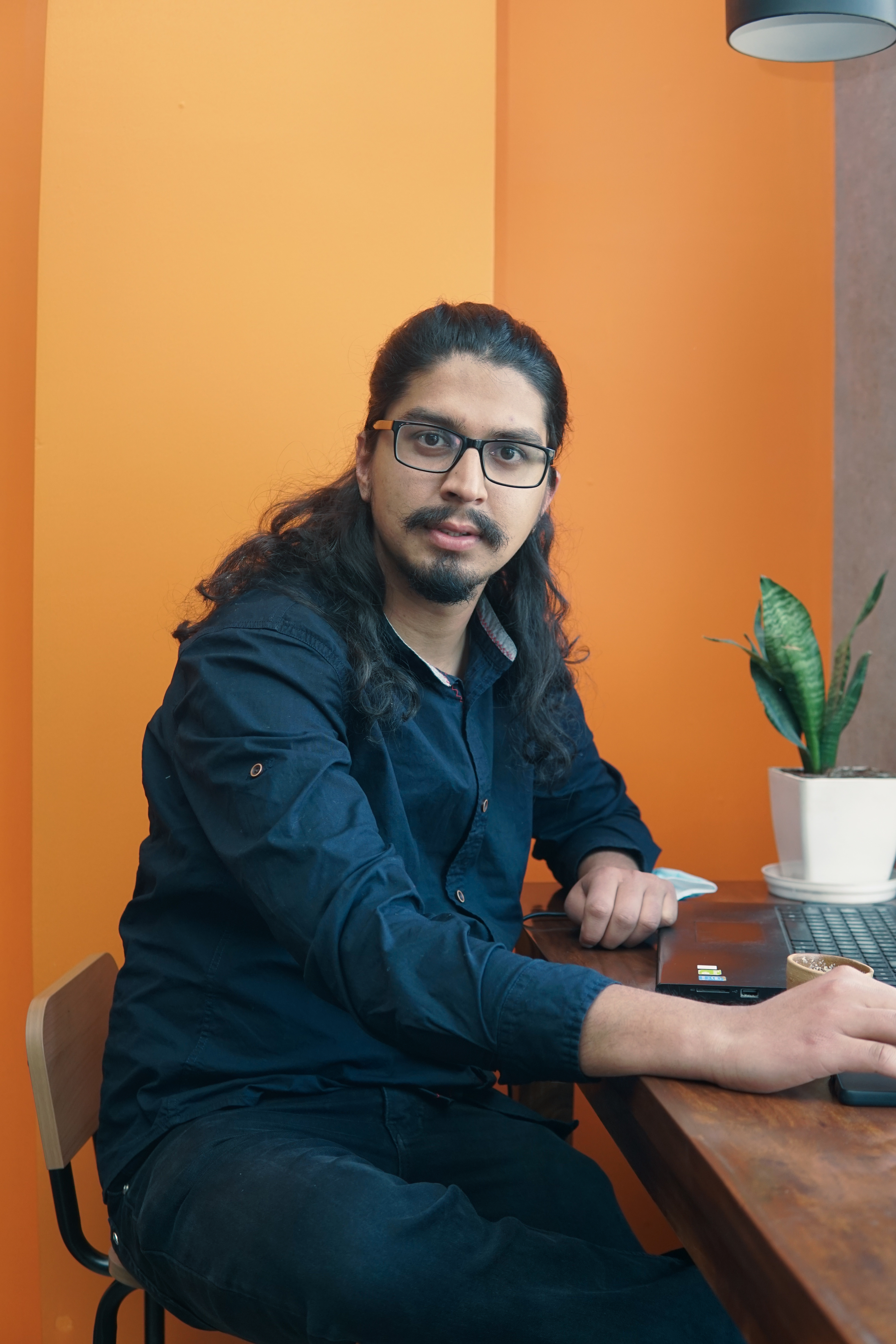 Aakrit waving, typing, thinking, drinking coffee, and gesturing at his desk